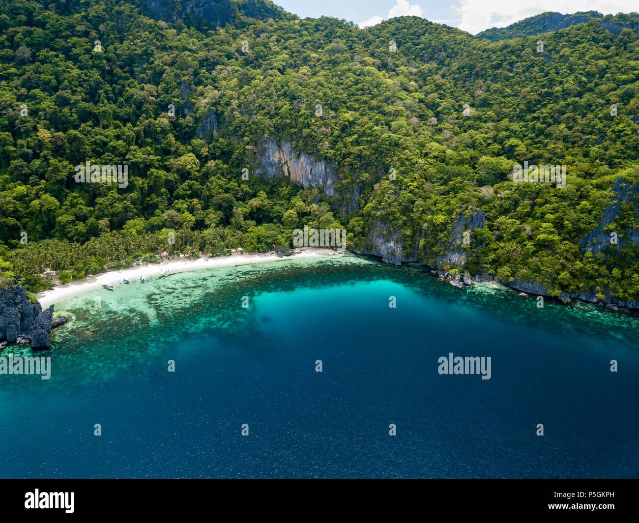 Aerial drone view of a spectacular tropical beach surrounded by dense jungle and jagged cliffs (Papaya Beach, Palawan) Stock Photo