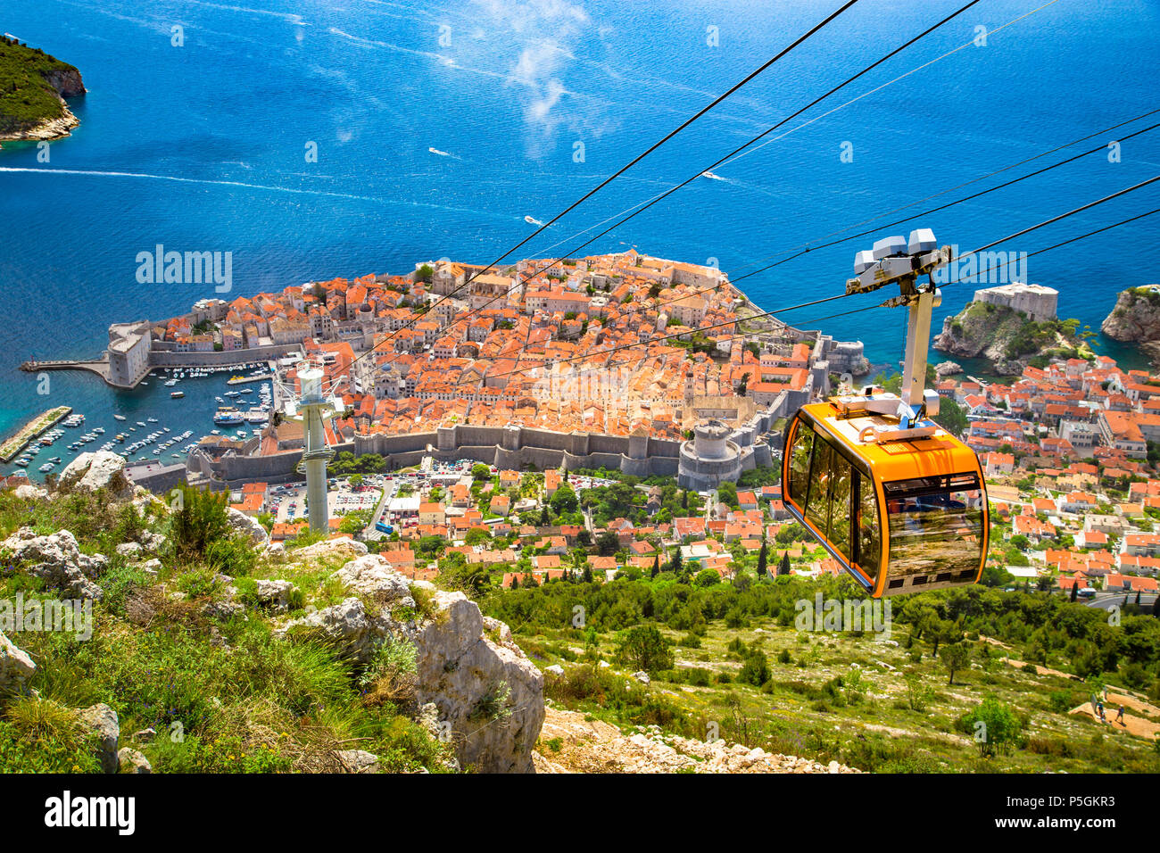 Aerial panoramic view of the old town of Dubrovnik with famous Cable Car on Srd mountain on a sunny day with blue sky and clouds in summer, Croatia Stock Photo