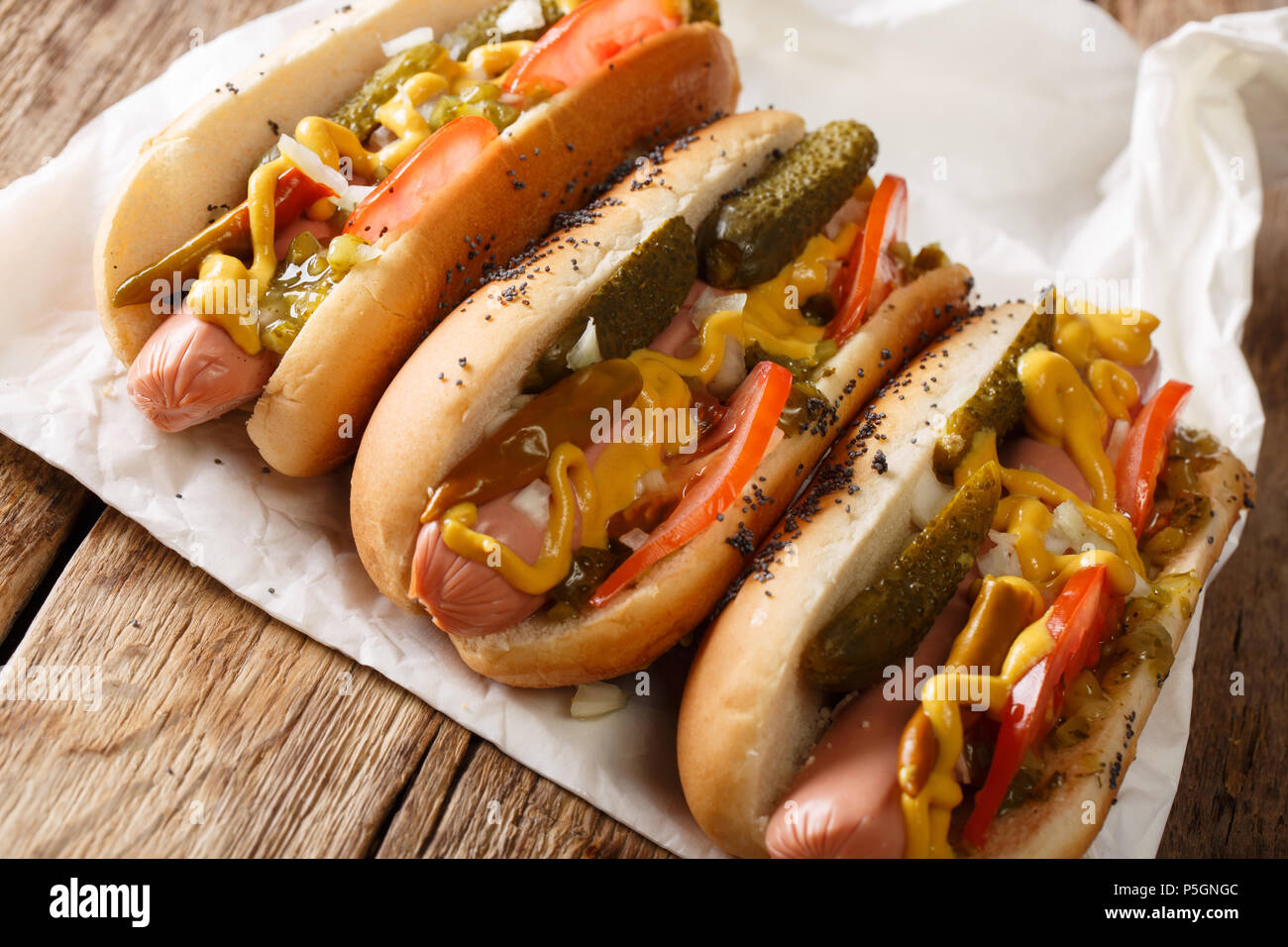Homemade Chicago style hot dogs with mustard, tomatoes, pickled cucumbers, onions and relish close-up on the table. horizontal Stock Photo