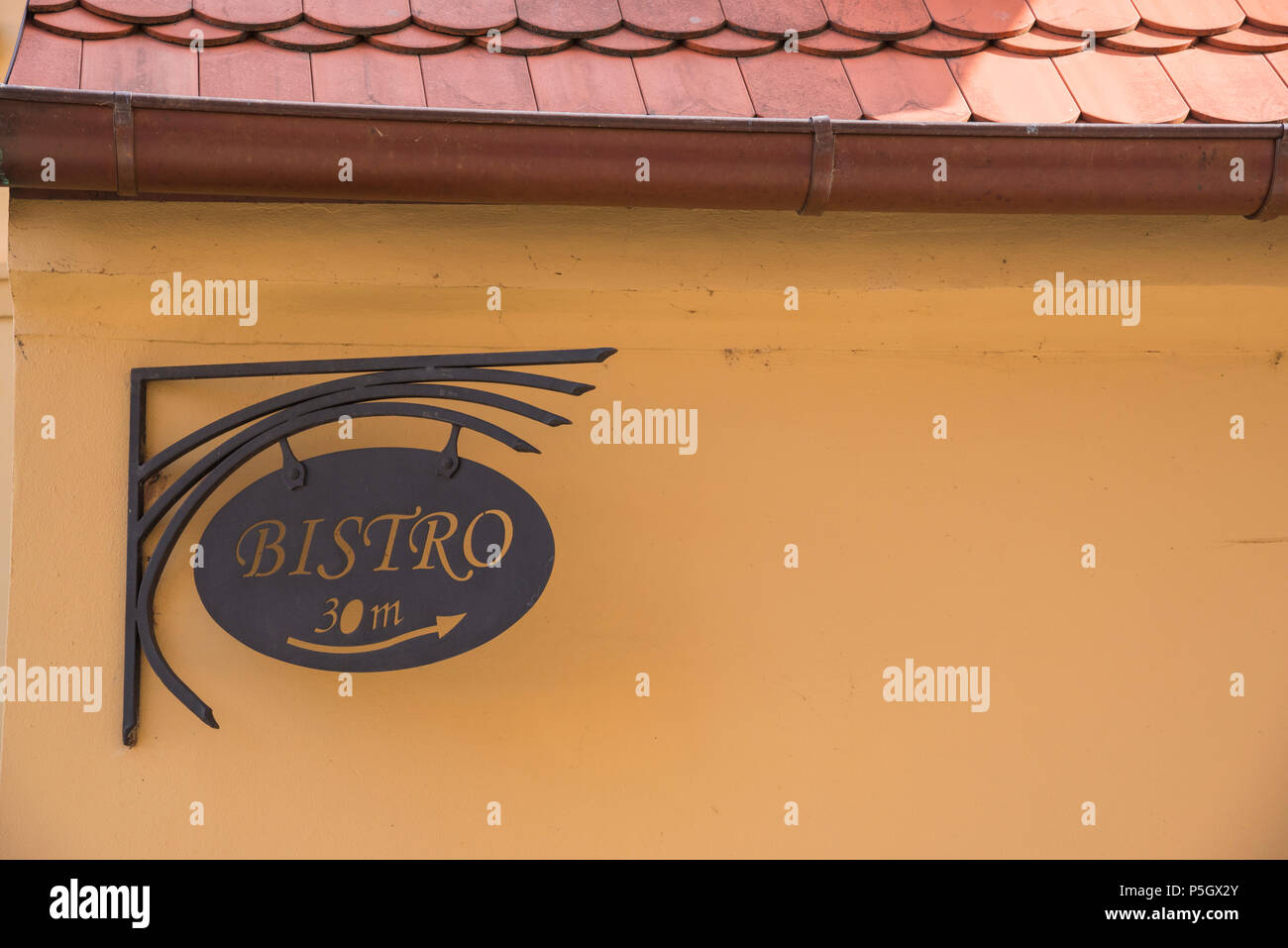 Bistro sign on a yellow wall with red-tiled roofing Stock Photo