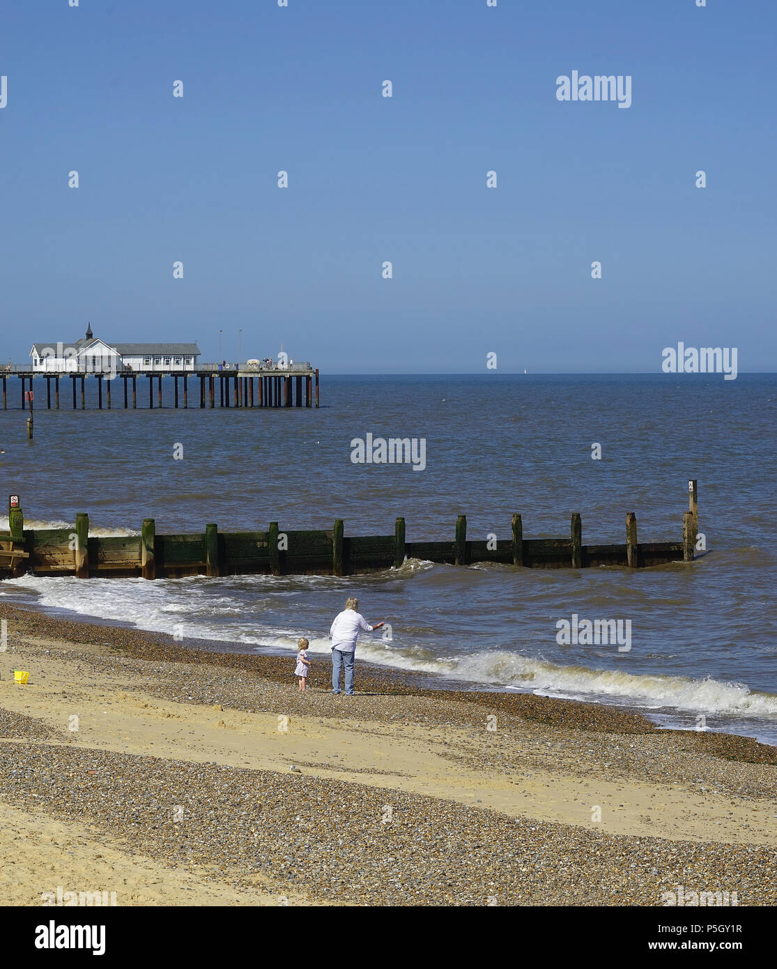 Casting pebbles to the waves on Southwold Beach Stock Photo