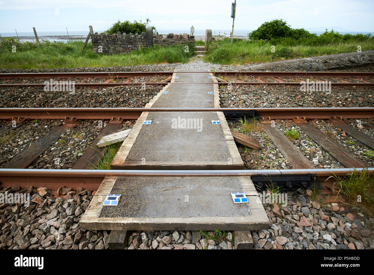 small unmanned pedestrian level crossing on coastal train track Cumbria England UK Stock Photo