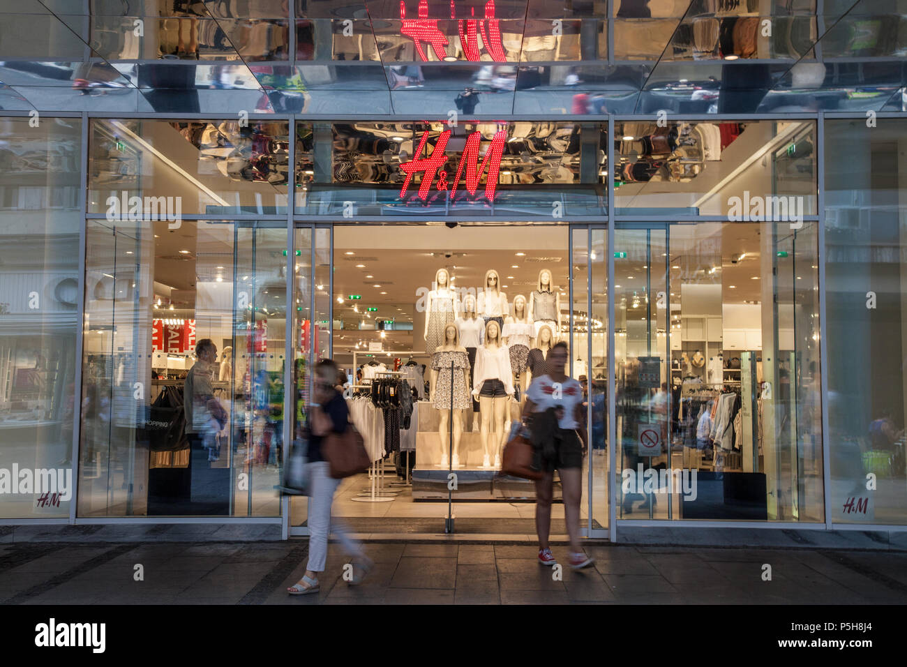 BELGRADE, SERBIA - APRIL 14, 2018:  Clients going outof an H&M store in the Serbian capital city, a giant logo of H&M can be seen above the main entra Stock Photo