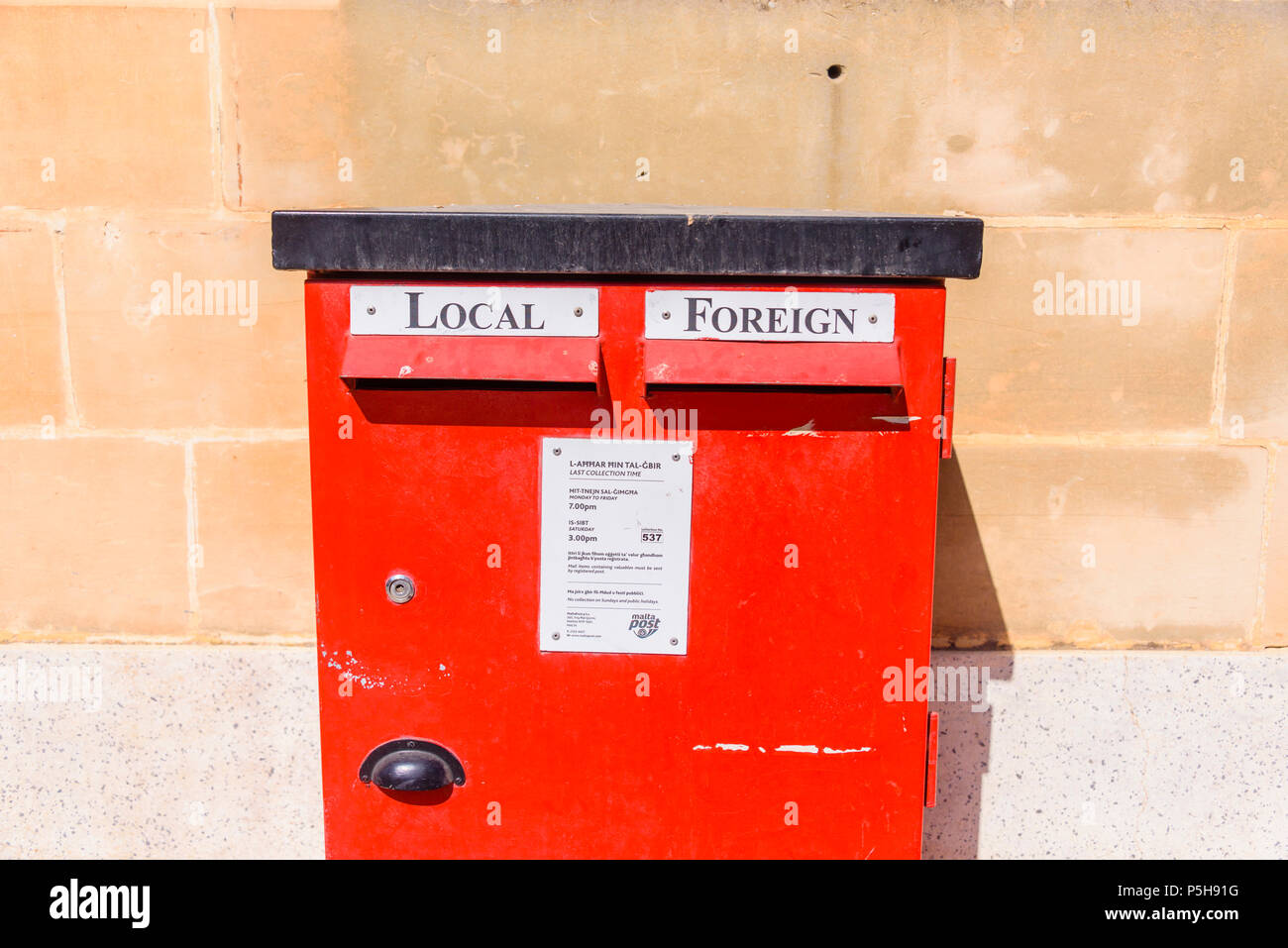 Red letterbox with slots for local and foreign mail and collection times from Malta Post. Stock Photo