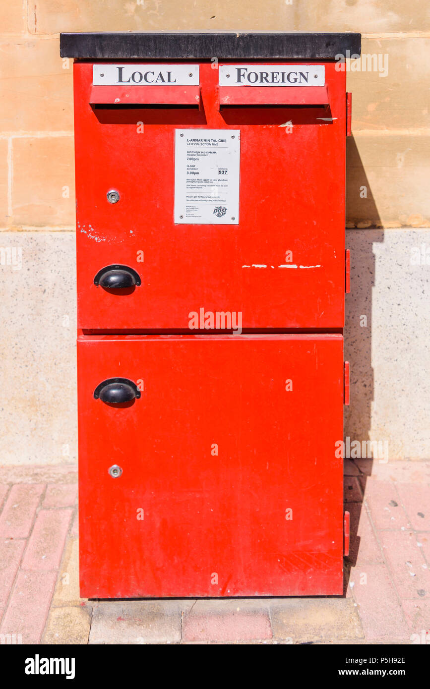 Red letterbox with slots for local and foreign mail and collection times from Malta Post.g Stock Photo