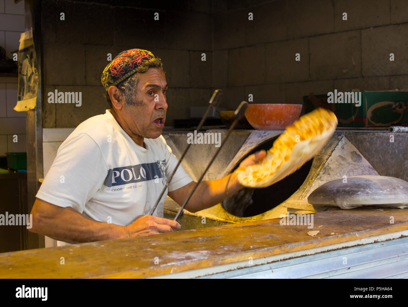 9 May 2018 An elderly Jewish male in a colourful hat making pita bread in a small home bakery near the Mahane Yehuda street market in Jerusalem Israel Stock Photo