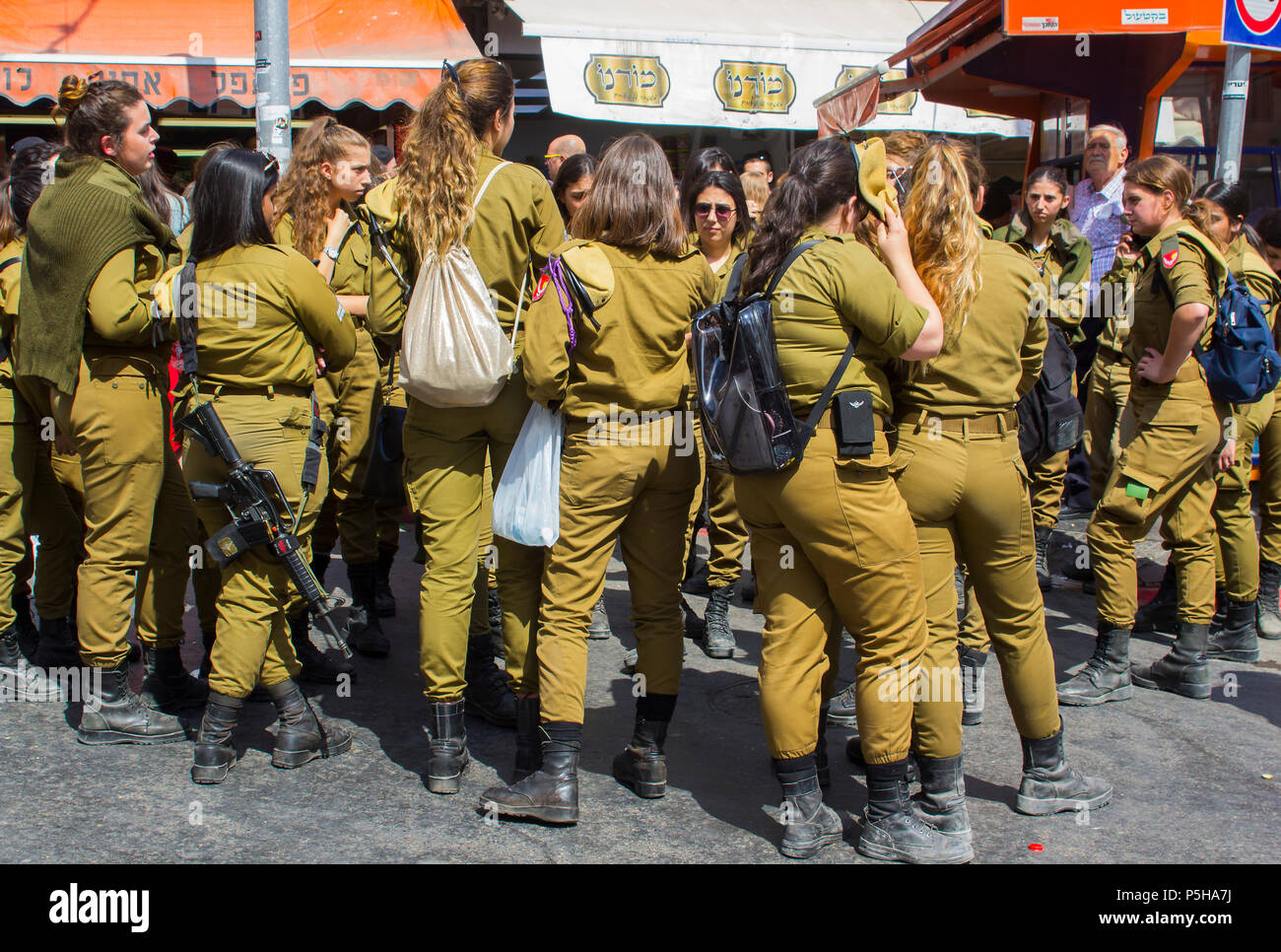 9 May 2018 A small group of off duty female Israeli Army conscripts with an armed guard laugh and chat together at the Mahane Yehuda market Jerusalem Stock Photo