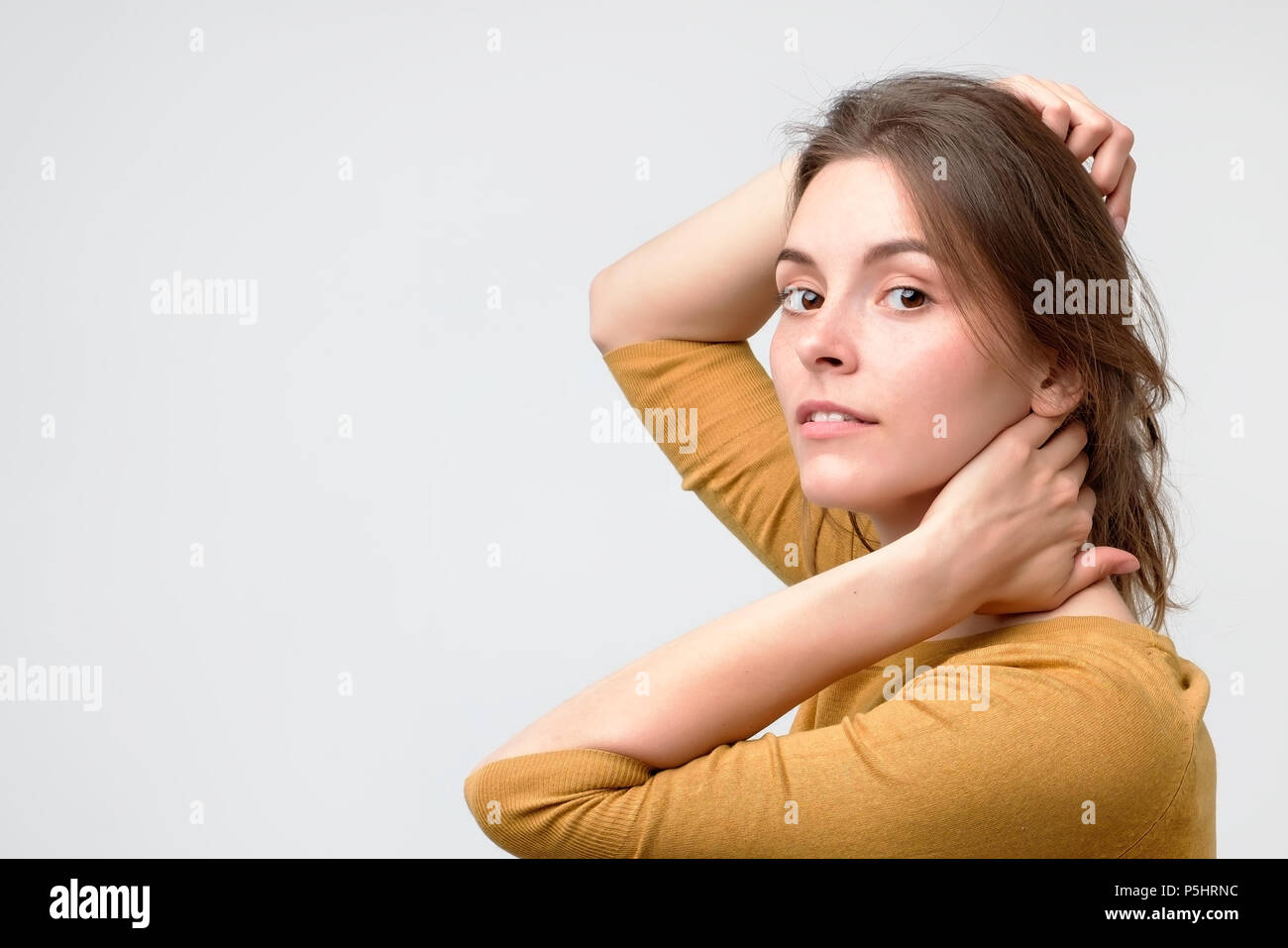 Young european woman in yellow sweater with beautiful smile in studio. Portrait on gray background. Stock Photo