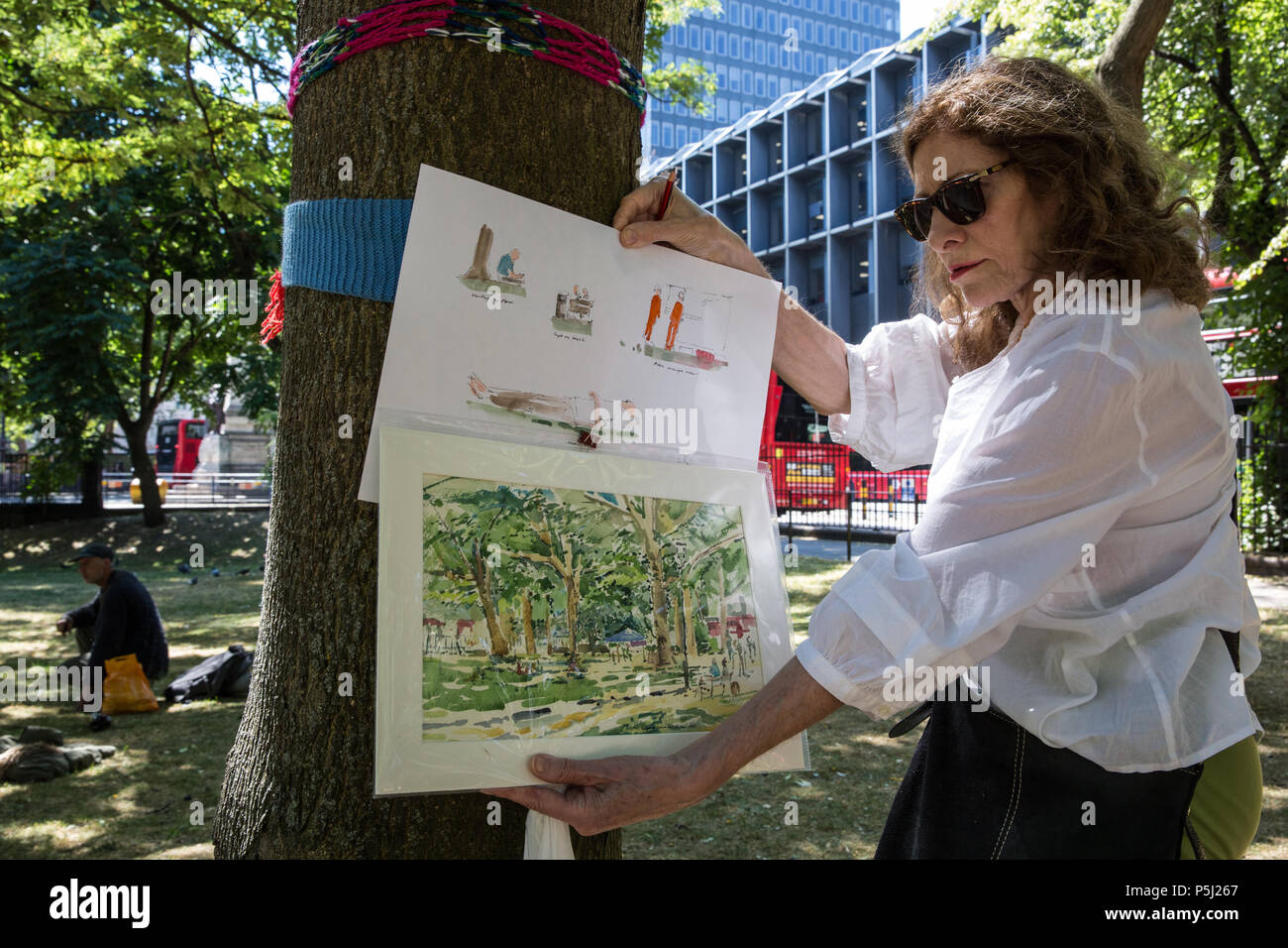 London, UK. 26th June 2018. Local resident Primavera Boman-Behram holds images of trees in Euston Square Gardens and construction workers on site as part of a protest using art against the felling of mature trees to make way for temporary sites for construction vehicles and a displaced taxi rank as part of preparations for the HS2 rail line. The protest, involving the capturing of images of the trees on paper using a variety of different techniques, was hosted by the artist Dan Llywelyn Hall as 'The Last Stand Against the Environmental Damage of HS2'. Credit: Mark Kerrison/A Stock Photo