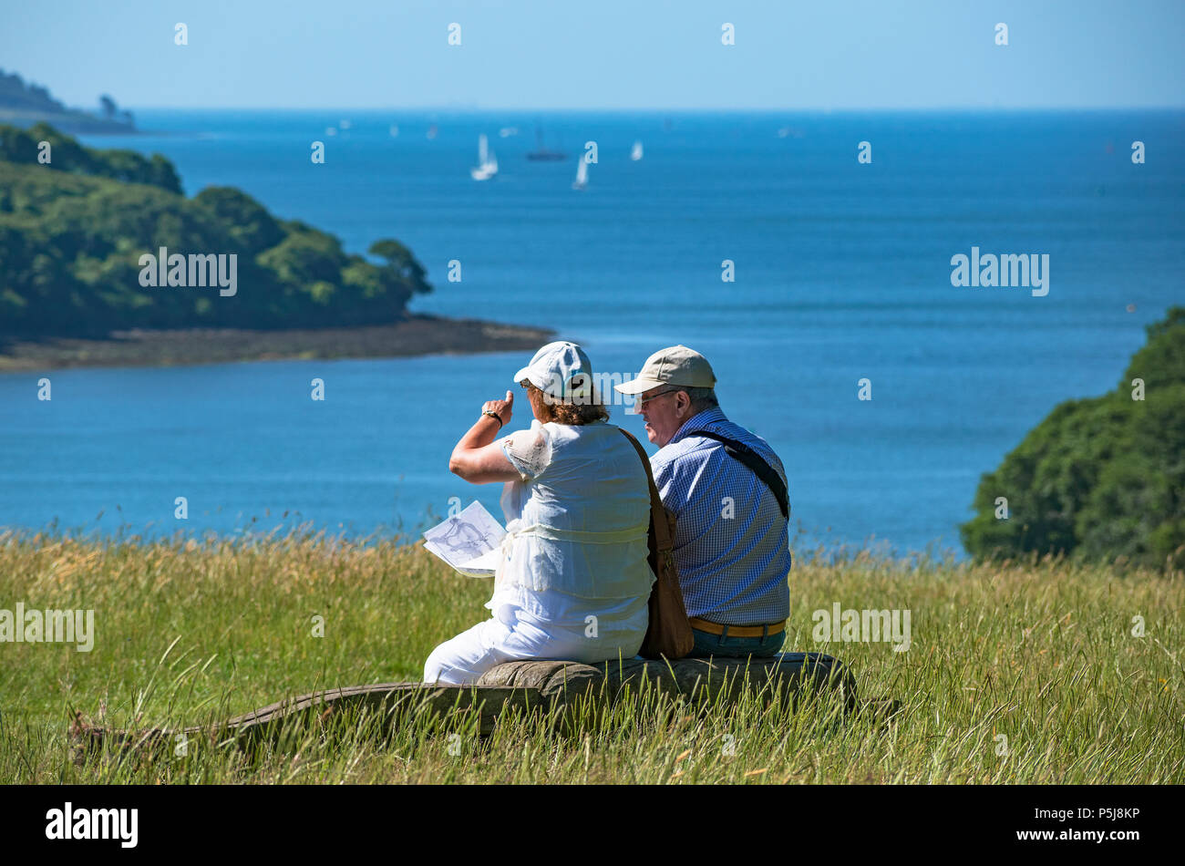 Trelissick, Cornwall, UK, 27th June 2018 UK Weather: With another hot day forecast a senior couple rest and enjoy the view across Falmouth Bay: Photo Credit Kevin Britland/Alamy LIve News. Stock Photo
