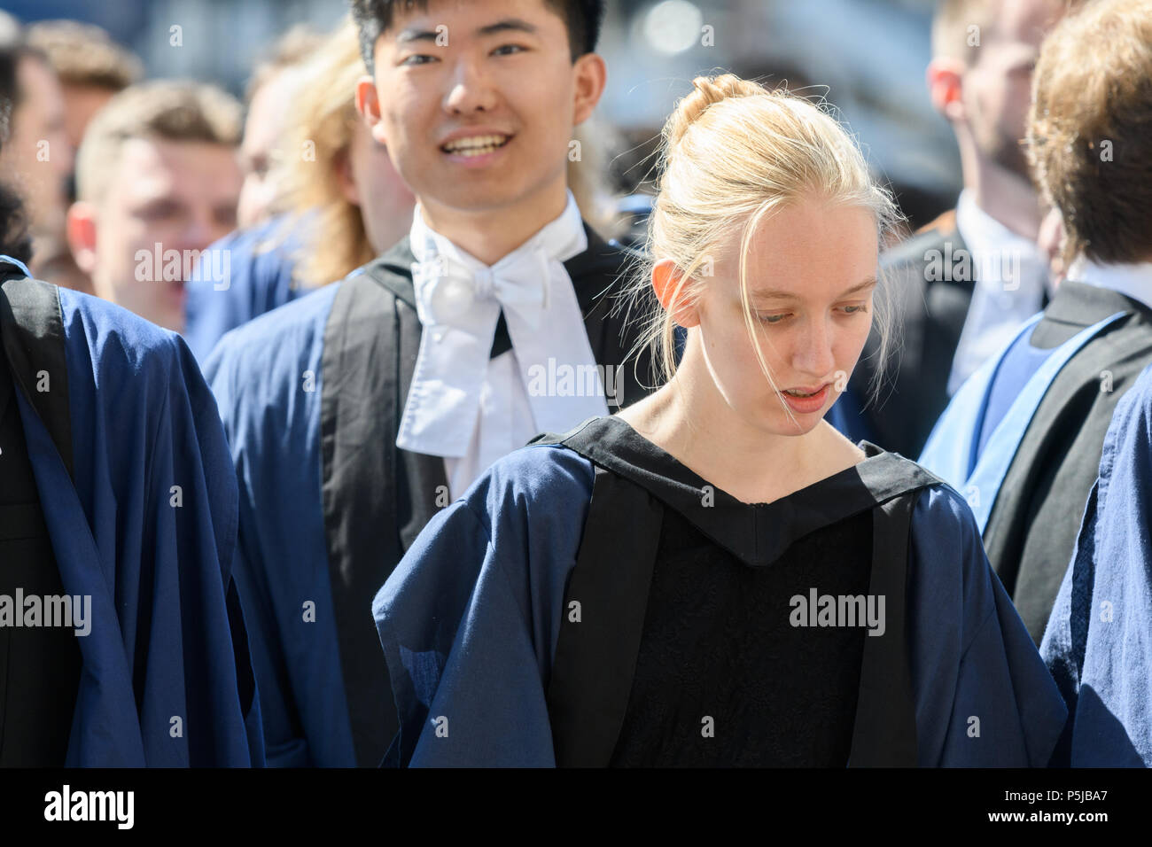 Cambridge, UK. Wednesday 27th June 2018. Dressed in formal academic gowns,  graduands of Trinity college, Cambridge University, UK, wait in an orderly  queue to enter Senate House for the graduation/degree ceremony on