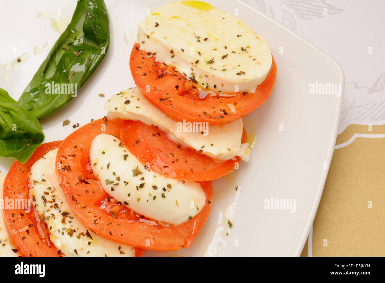 Delicious caprese salad with ripe tomatoes and mozzarella cheese with fresh basil leaves. Italian food. Stock Photo