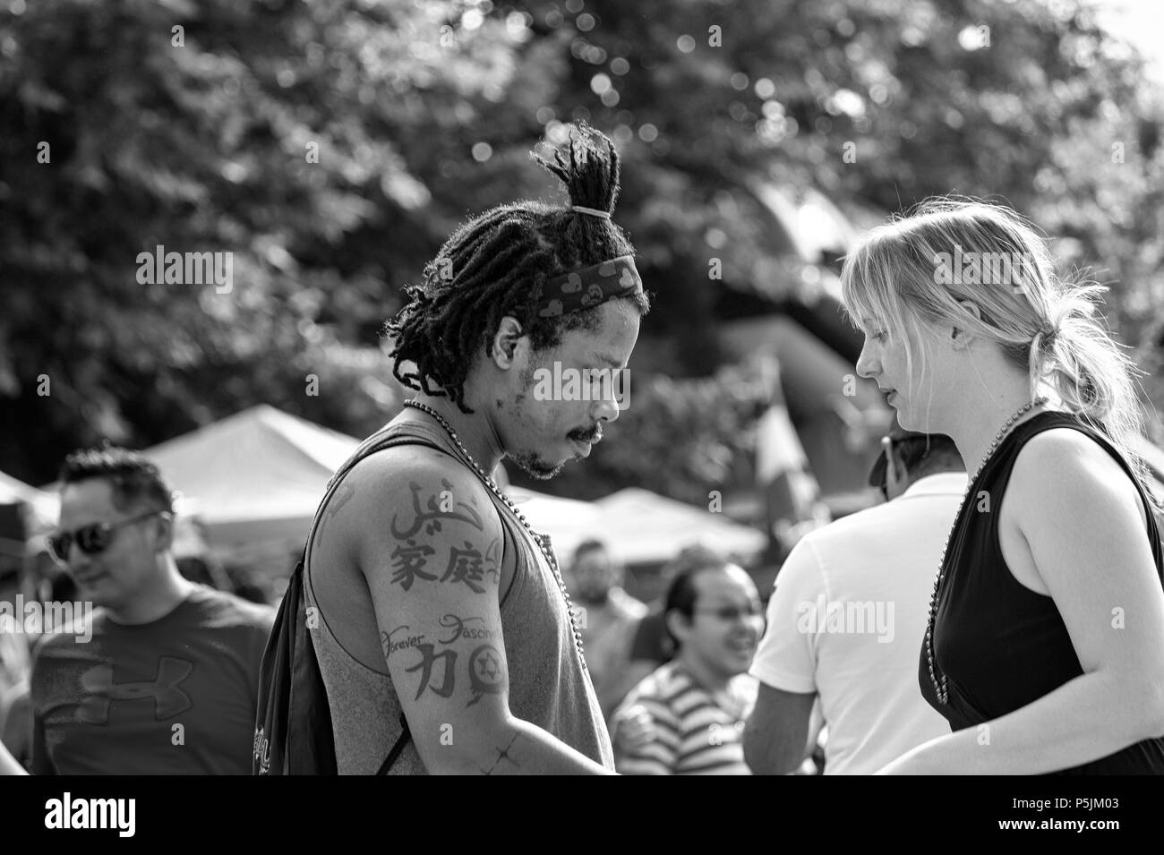 A young couple starts to dance at the outdoor festival Hola Carolina Asheville, in NC, USA,  looking a little shy. Stock Photo
