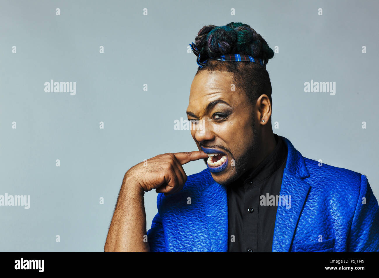 Portrait of a man in blue jacket and blue lips biting his finger Stock Photo