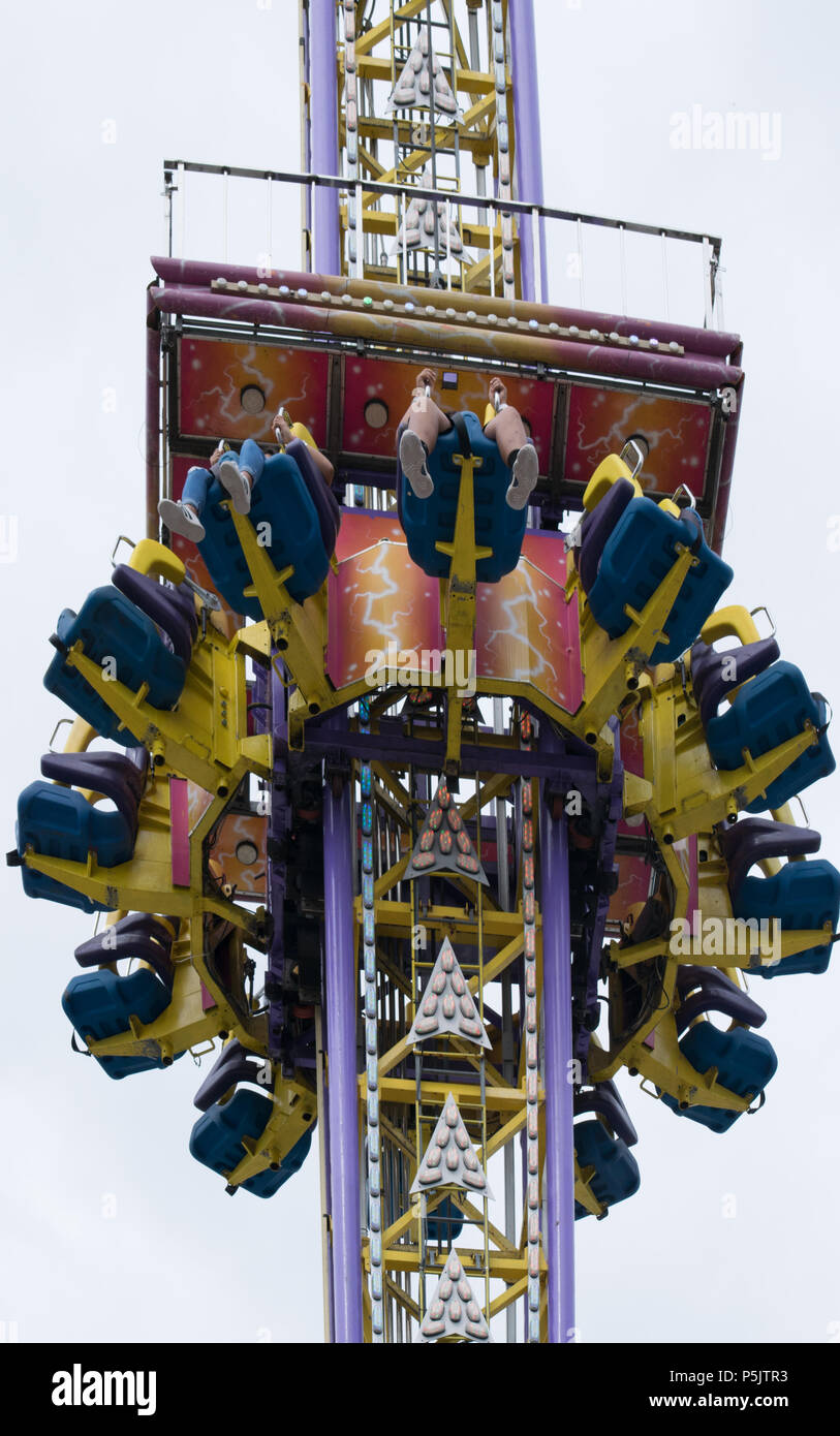 Two teens dangle four feet suspended high above the midway at the fair Stock Photo