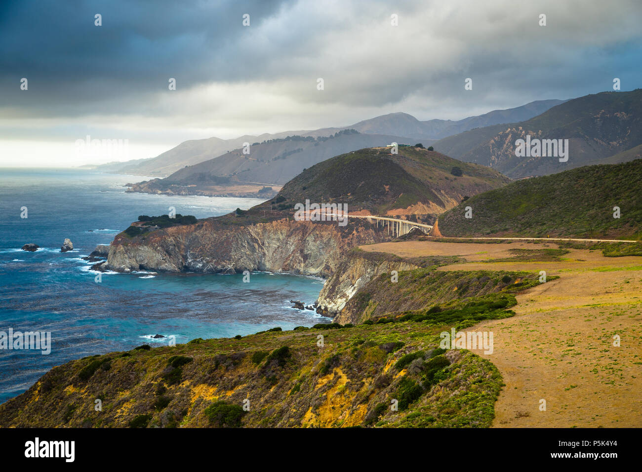 Scenic panoramic view of the beautiful coastline of Big Sur with historic Bixby Creek Bridge along world famous Highway 1 with dramatic cloudscape in  Stock Photo