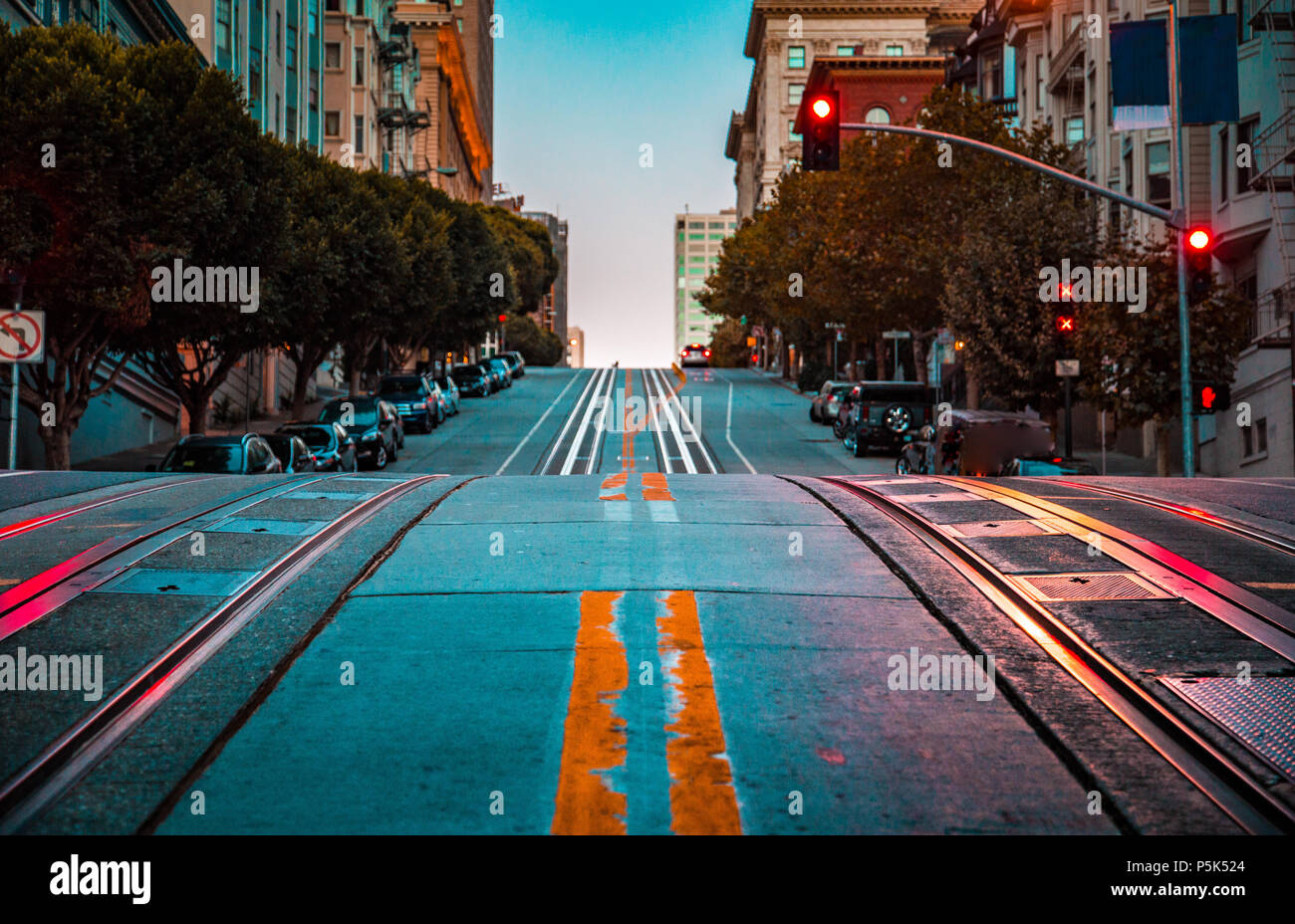 Low angle twilight view of an empty road with cable car tracks leading up a steep hill at famous California Street at dawn, San Francisco, California, Stock Photo