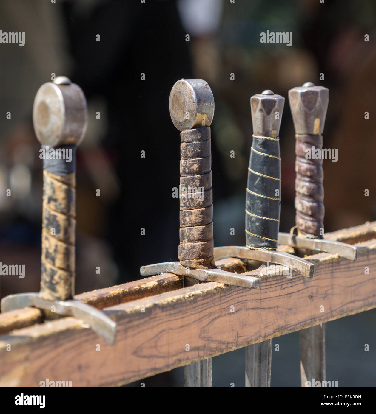 Handles of historical swords hung in a row on a medieval market, Germany Stock Photo