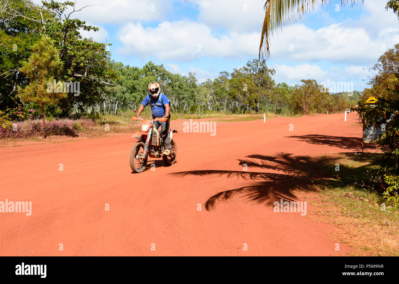 Motorbiker riding a dirt bike on a remote red dirt road, Cape York Peninsula, Far North Queensland, FNQ, QLD, Australia Stock Photo