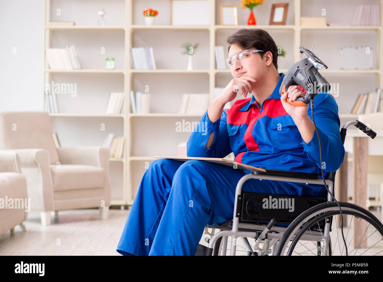 Disabled man working with handsaw at home Stock Photo