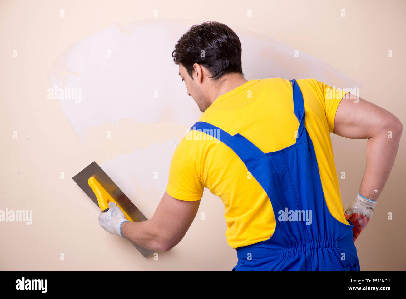 Young contractor employee applying plaster on wall Stock Photo