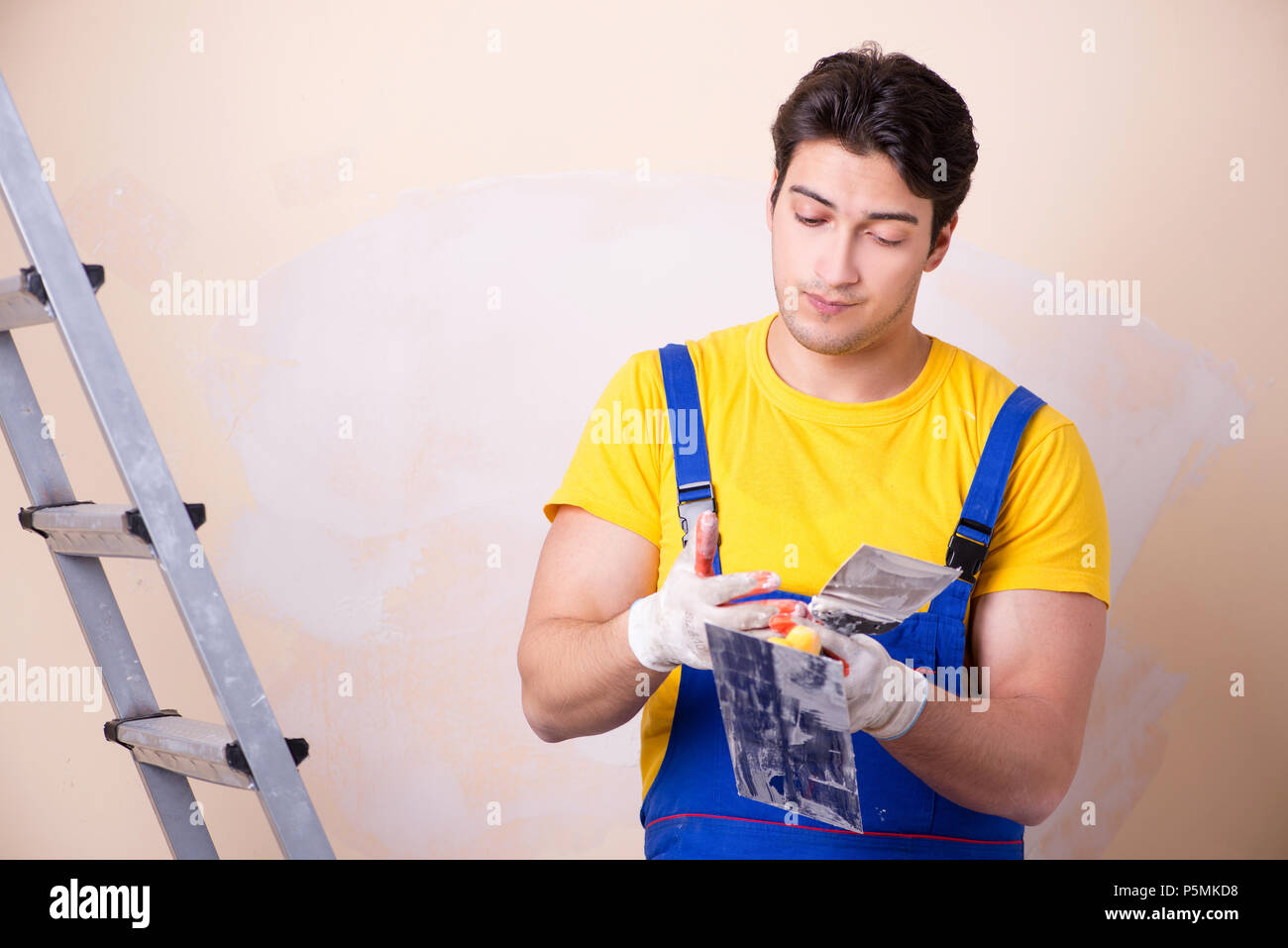 Young contractor employee applying plaster on wall Stock Photo