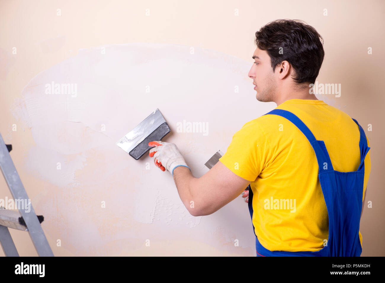 Young contractor employee applying plaster on wall Stock Photo