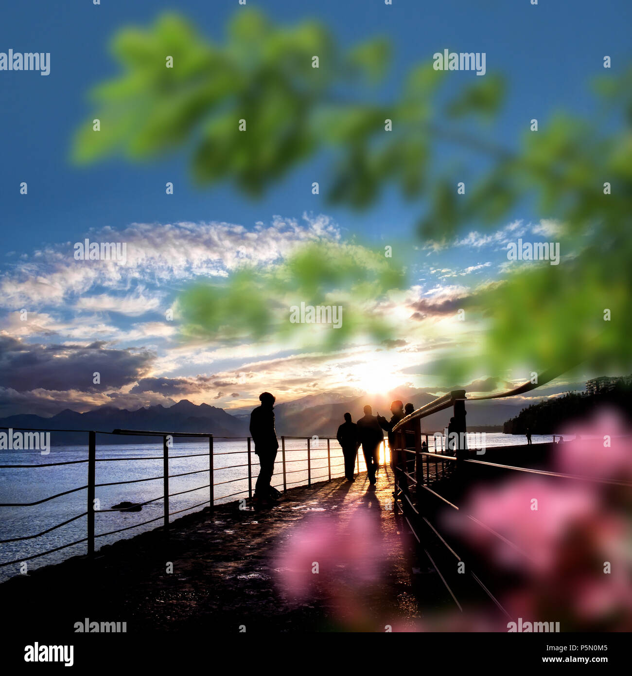 silhouetted people walking on street over sunset sky with sunbeam Stock ...