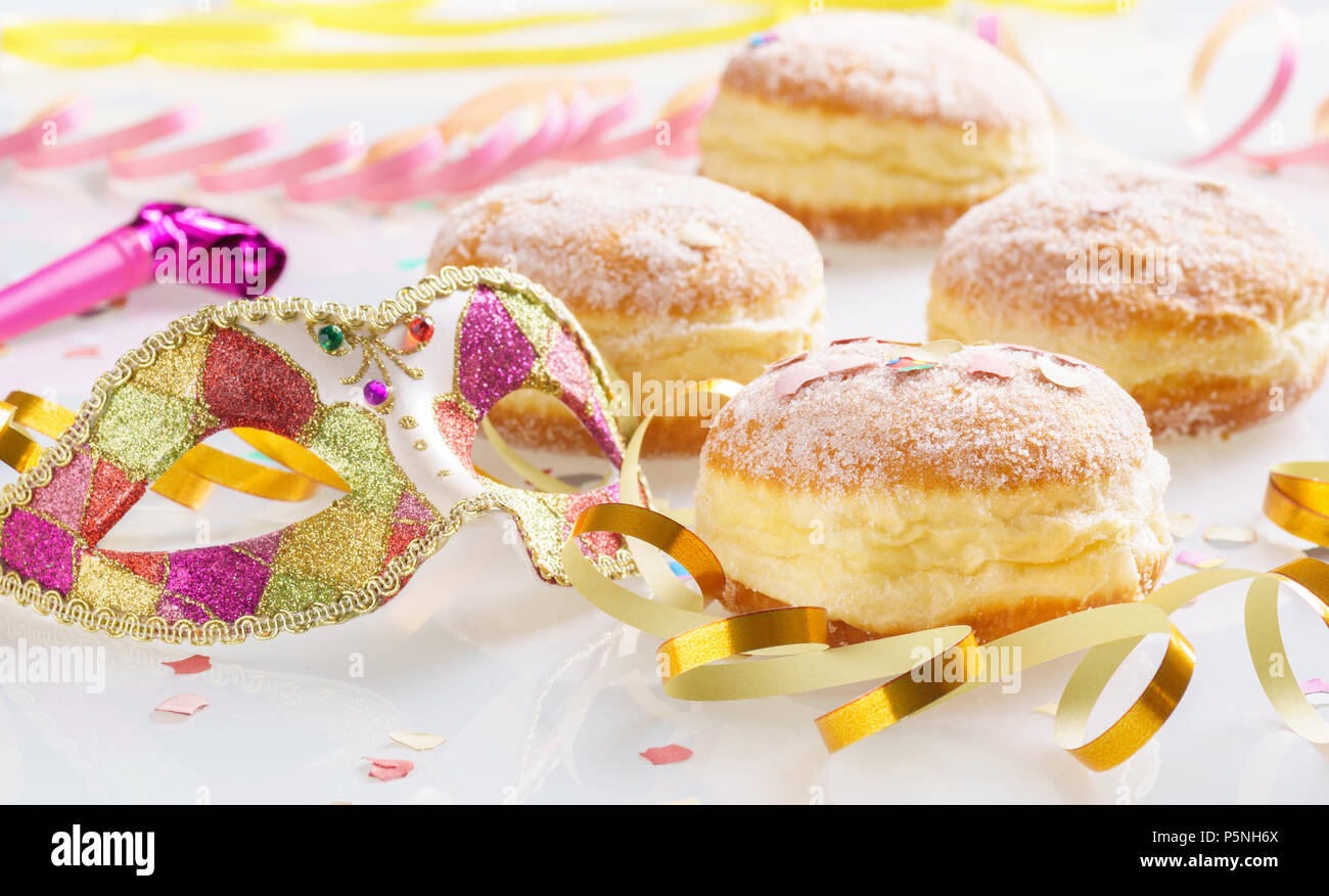 Carnival powdered sugar raised donuts with paper streamers and venetian mask. Stock Photo