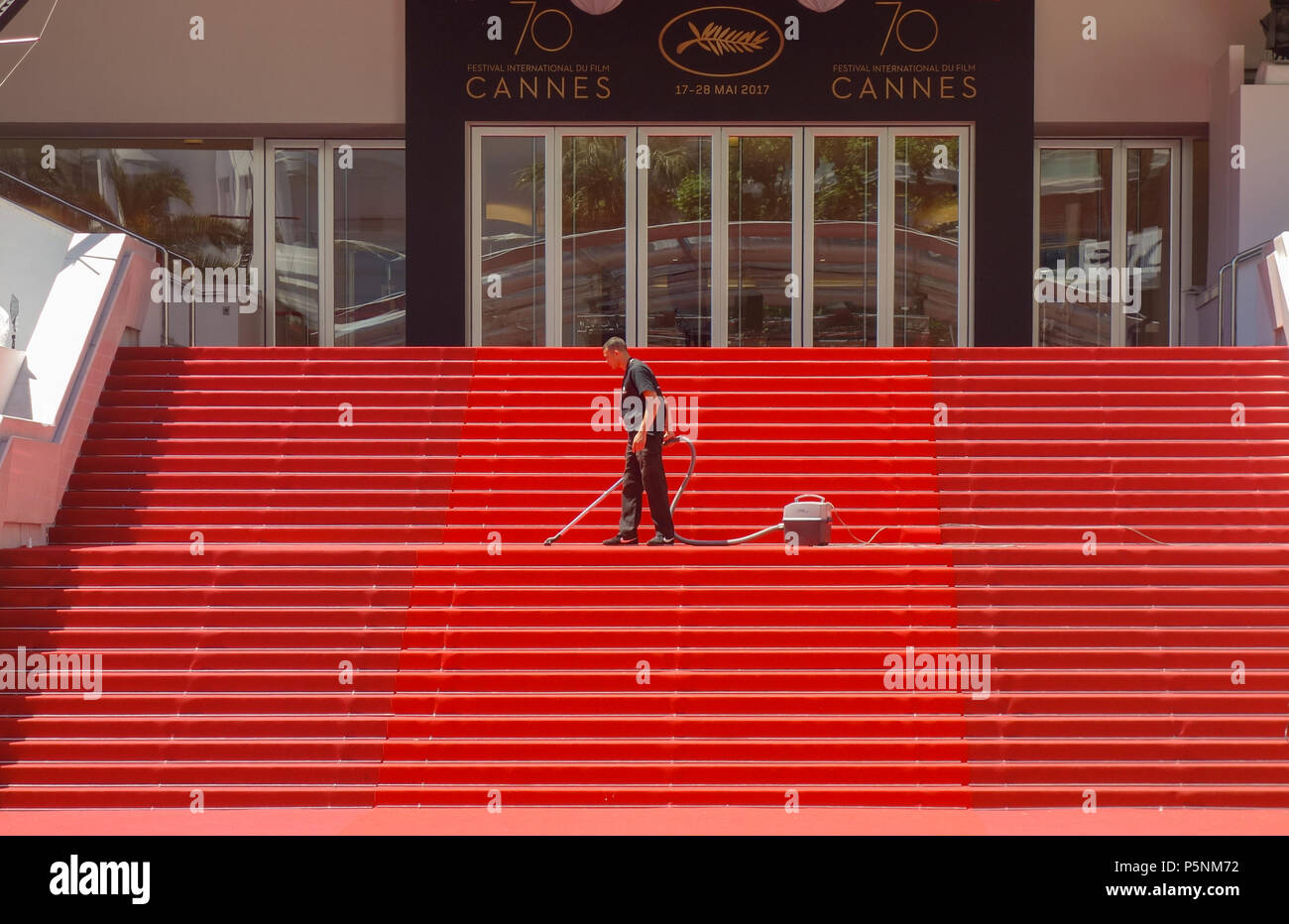 CANNES, FRANCE — MAY 19, 2017: A man vacuums the iconic red carpet steps ahead of festivities at the Cannes Film Festival. Stock Photo