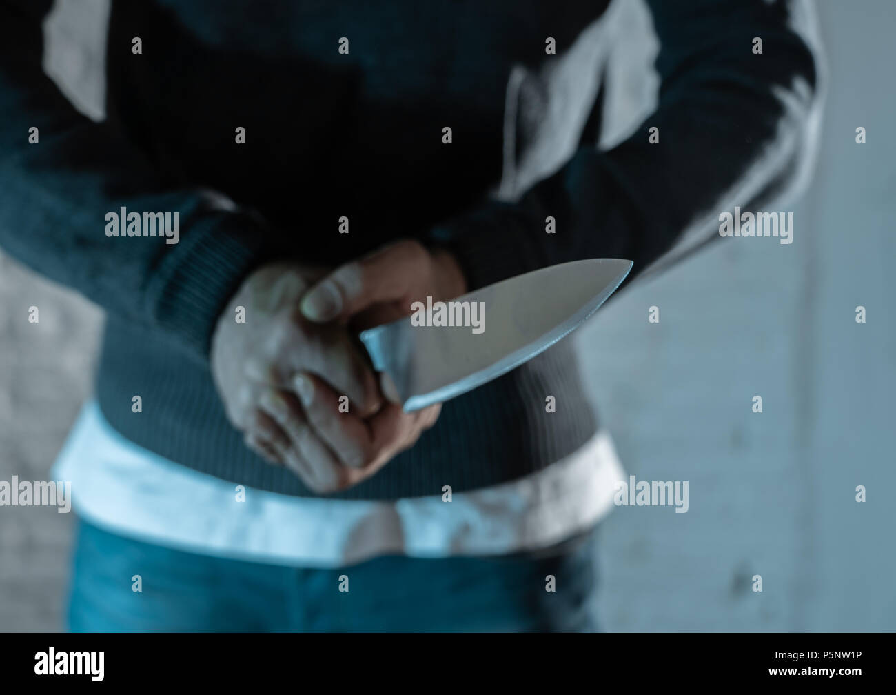close up of a hands holding a knife of dangerous hooded man standing in