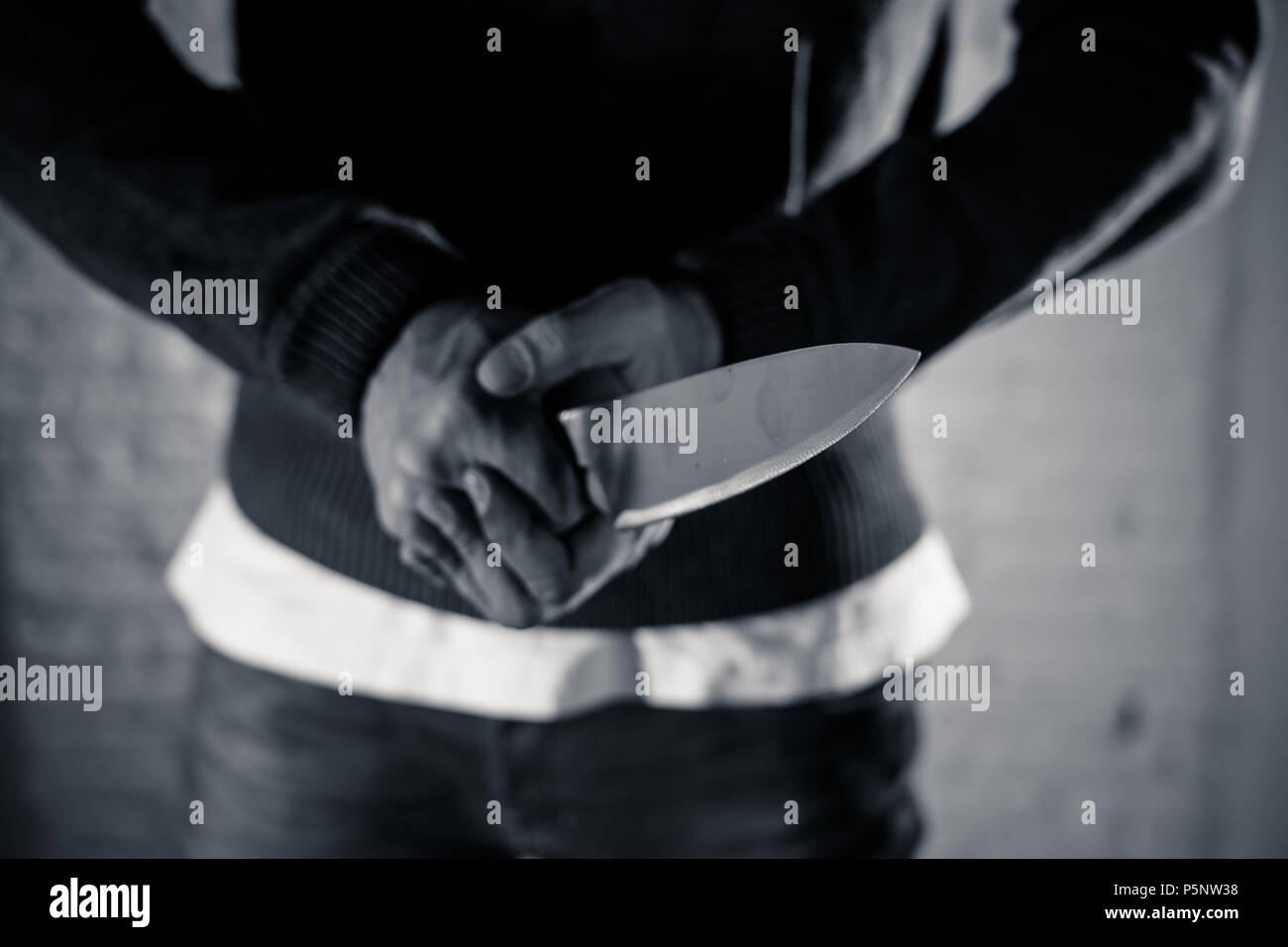 close up of a hands holding a knife of dangerous hooded man standing in