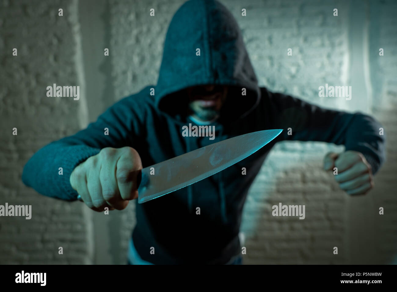 close up of a hands holding a knife of dangerous hooded man standing in