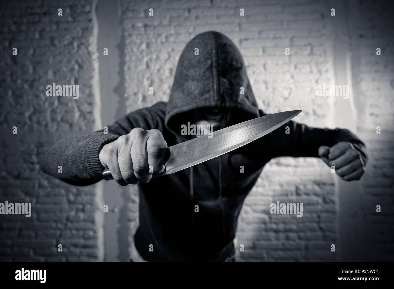 close up of a hands holding a knife of dangerous hooded man standing in