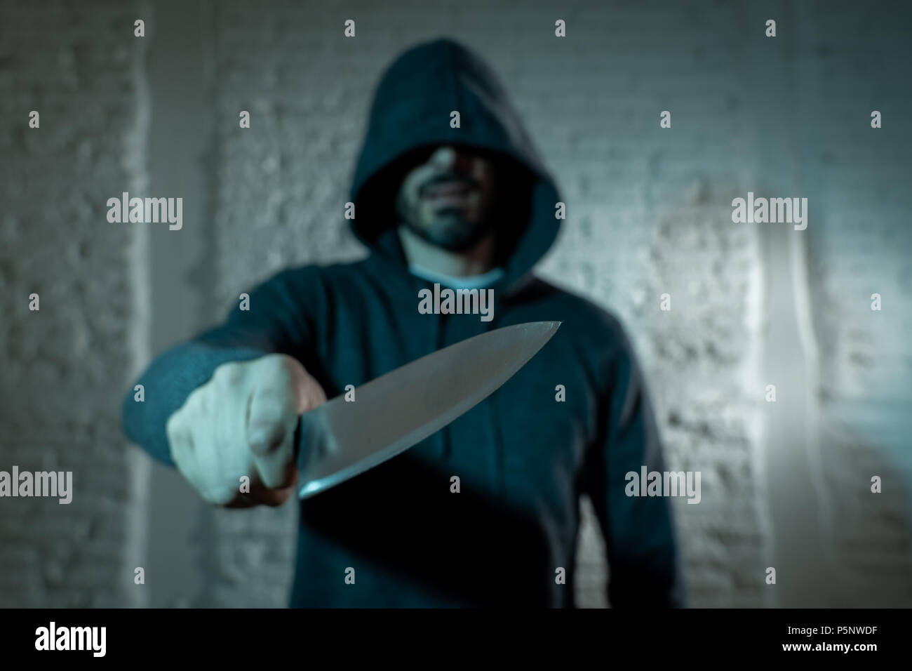 close up of a hands holding a knife of dangerous hooded man standing in