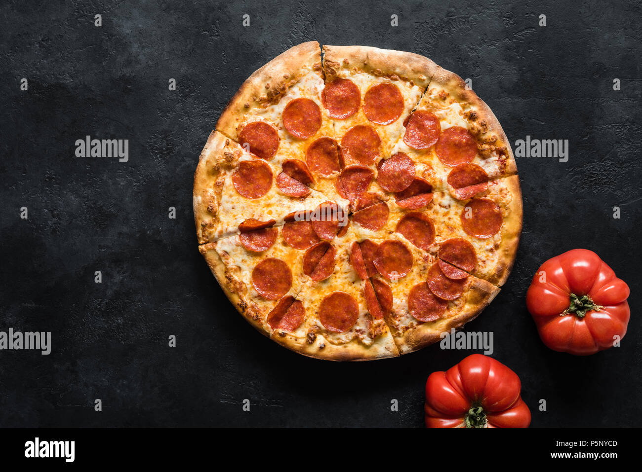 Pepperoni pizza on black concrete background. American pepperoni pizza, top view Stock Photo