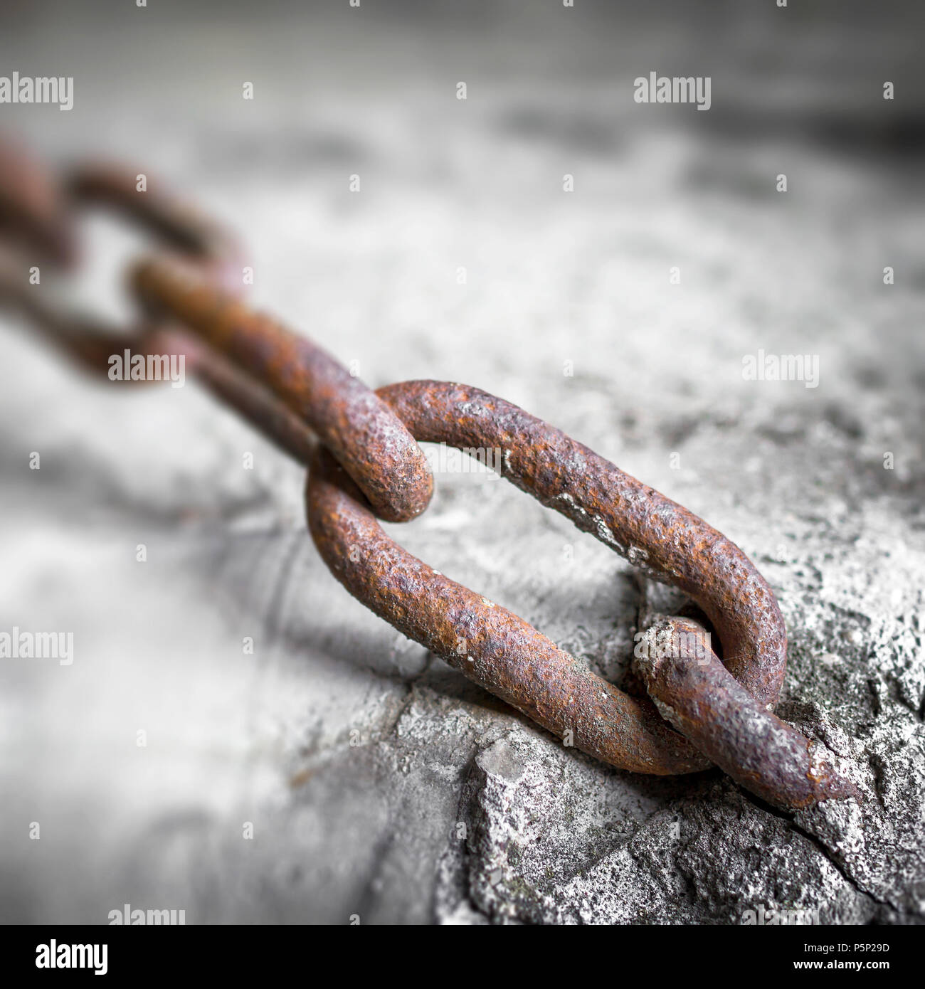 Closeup of rusted metal link of chain mounted in concrete. Shallow DOF ...