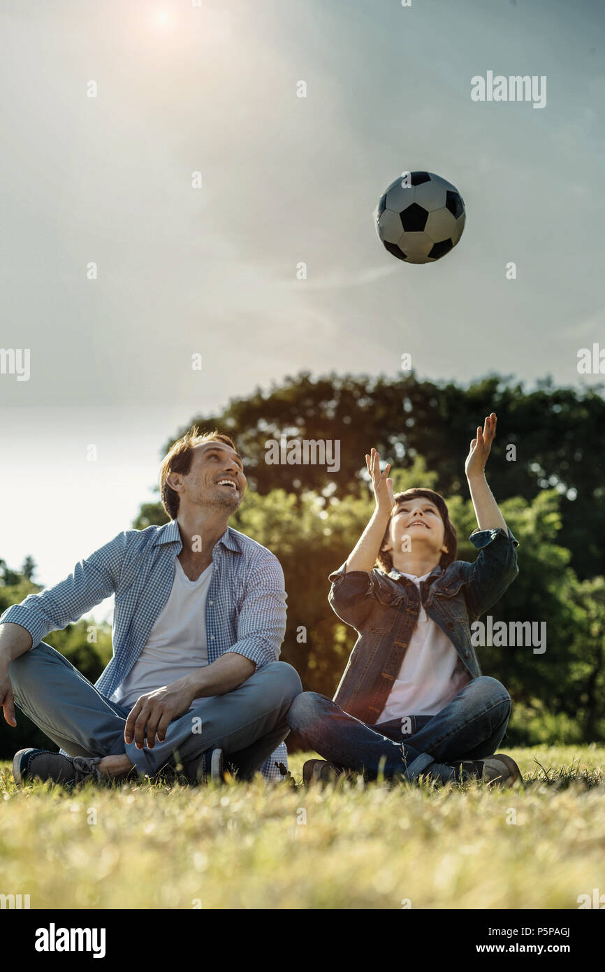 Smiling son and dad sitting on the grass Stock Photo - Alamy