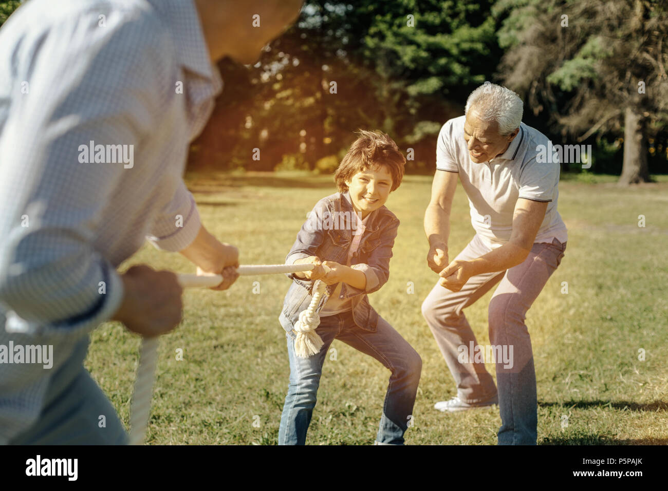 Son playing rope-pulling with dad and grandpa helping him Stock Photo ...