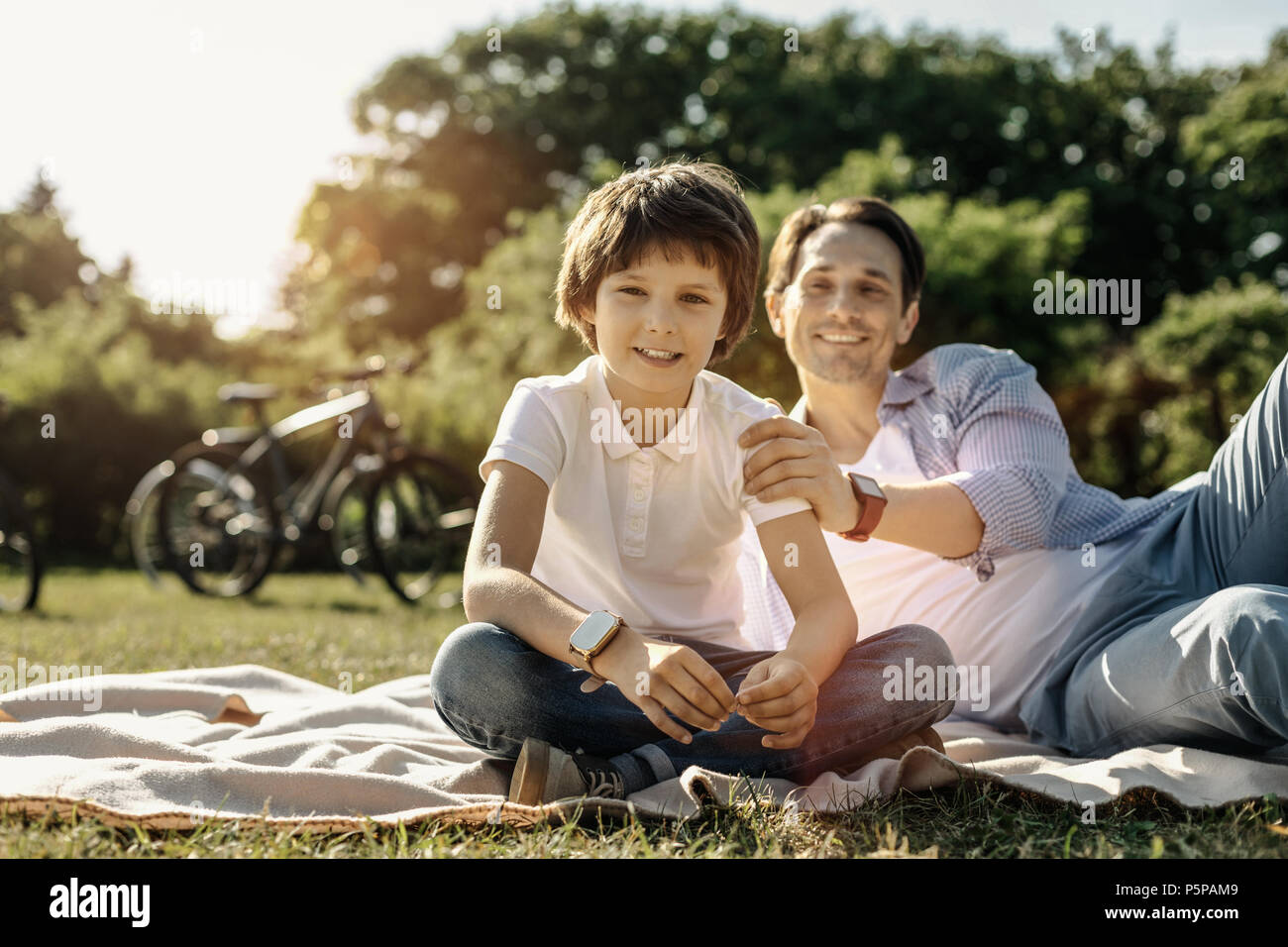 Smiling boy sitting on the grass with his dad Stock Photo - Alamy