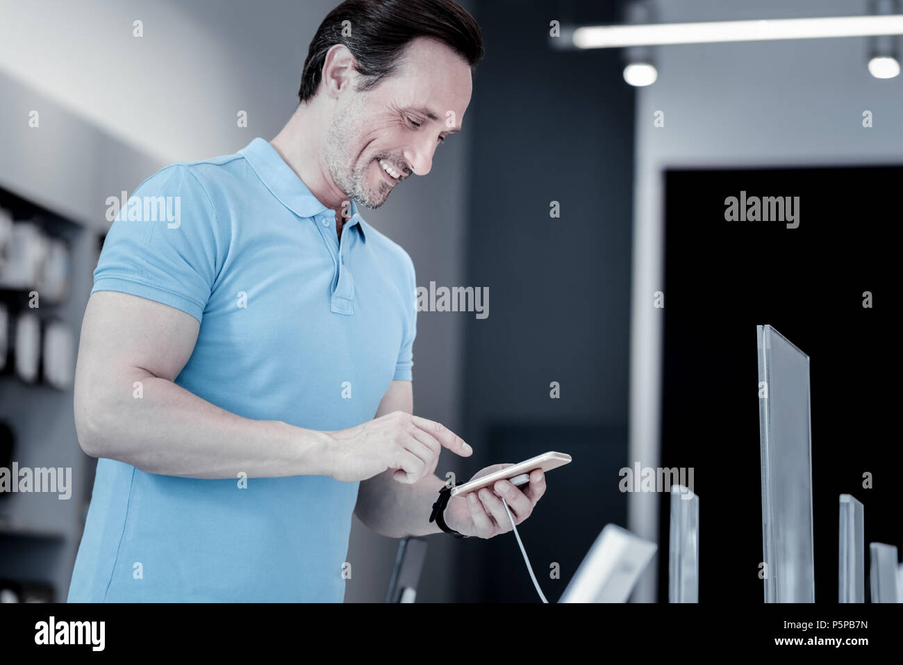 Pleasant young man standing with a smartphone Stock Photo