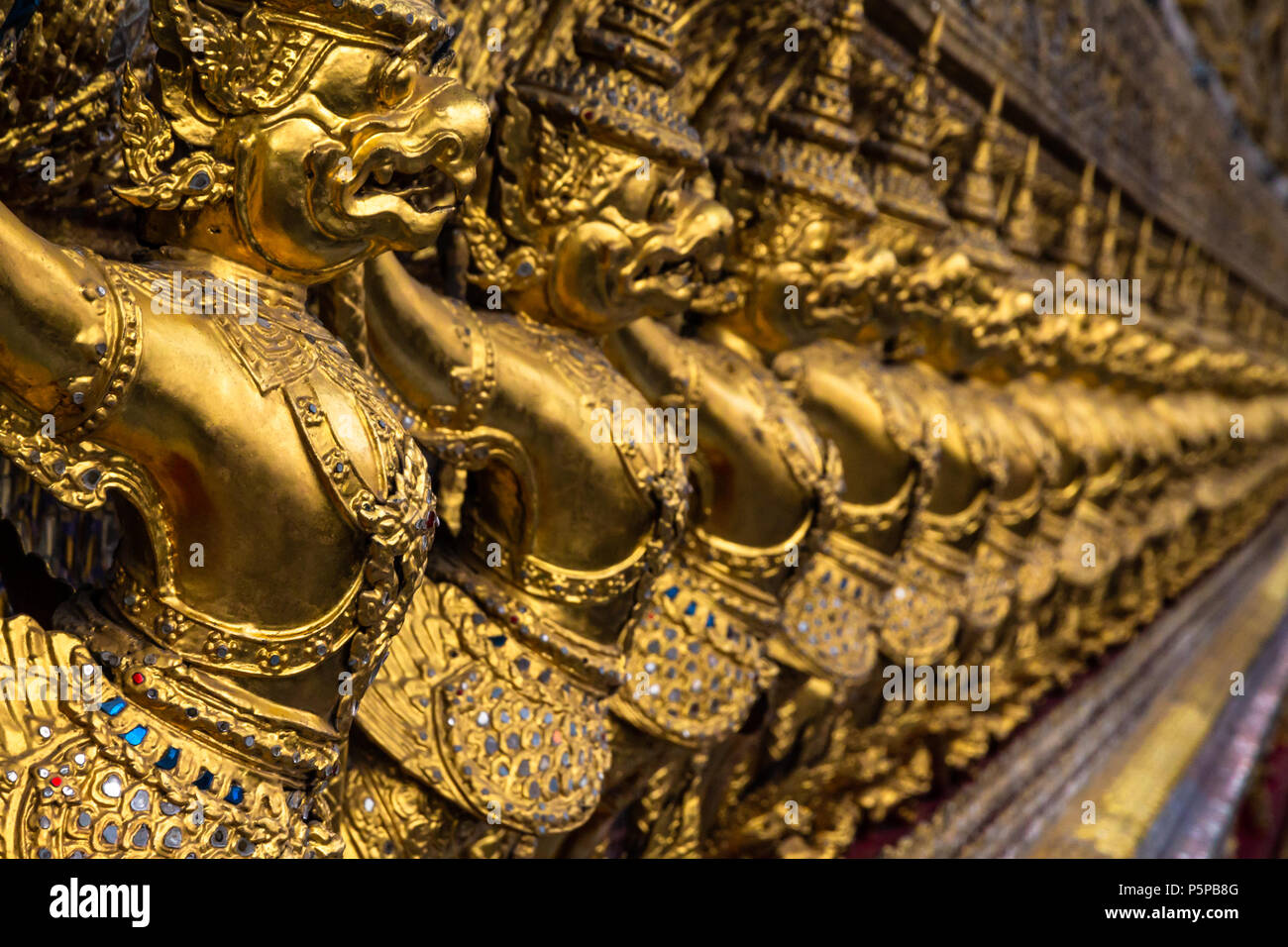 Row of golden Garuda figures from Thai mythology, adorning the interior of Wat Phra Kaew (Temple of the Emerald Buddha). Located in the Grand Palace, Stock Photo