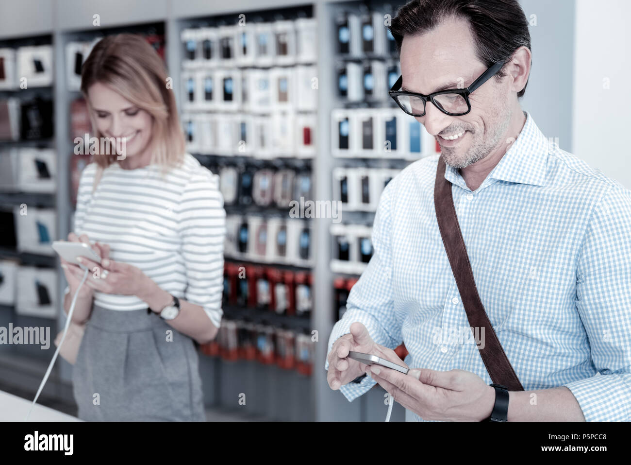 Calm customers testing devices in a shop Stock Photo - Alamy