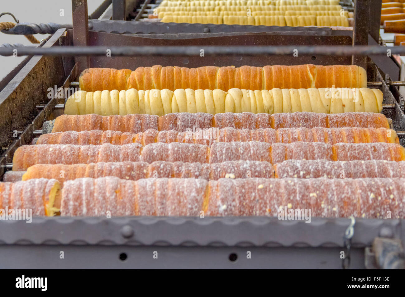 mostly central european spit cake speciality named Trdelnik rotating on a grill seen in the Czech Republic Stock Photo
