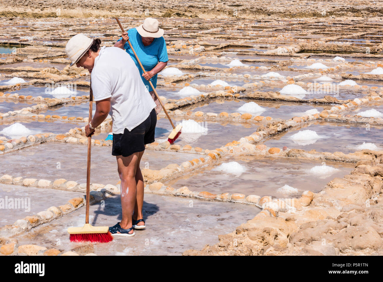 Harvesting sea salt from the ancient salt pans in Marsalforn, Gozo, Malta. Stock Photo