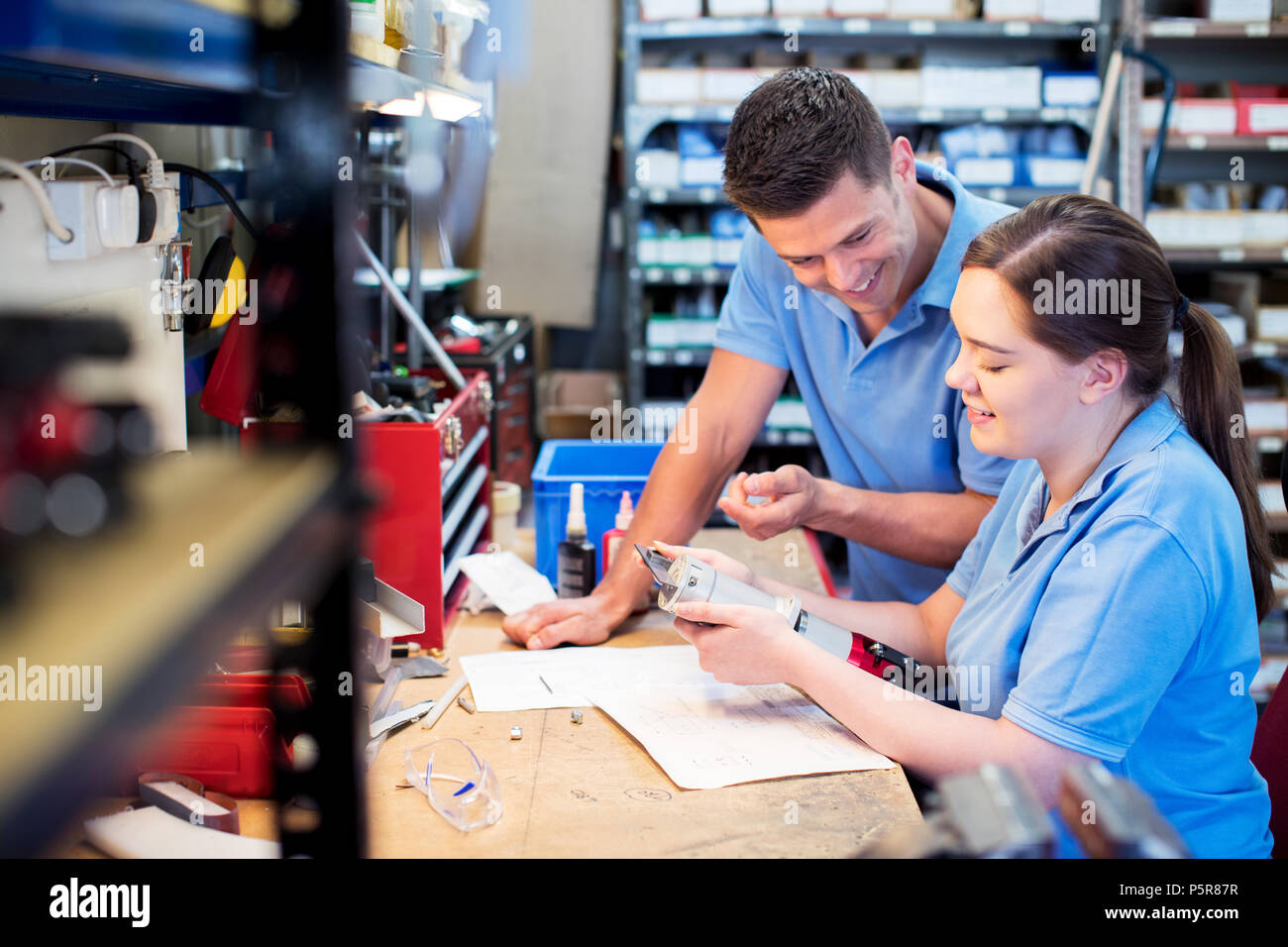 Engineer And Apprentice Examining Component At Workbench Stock Photo
