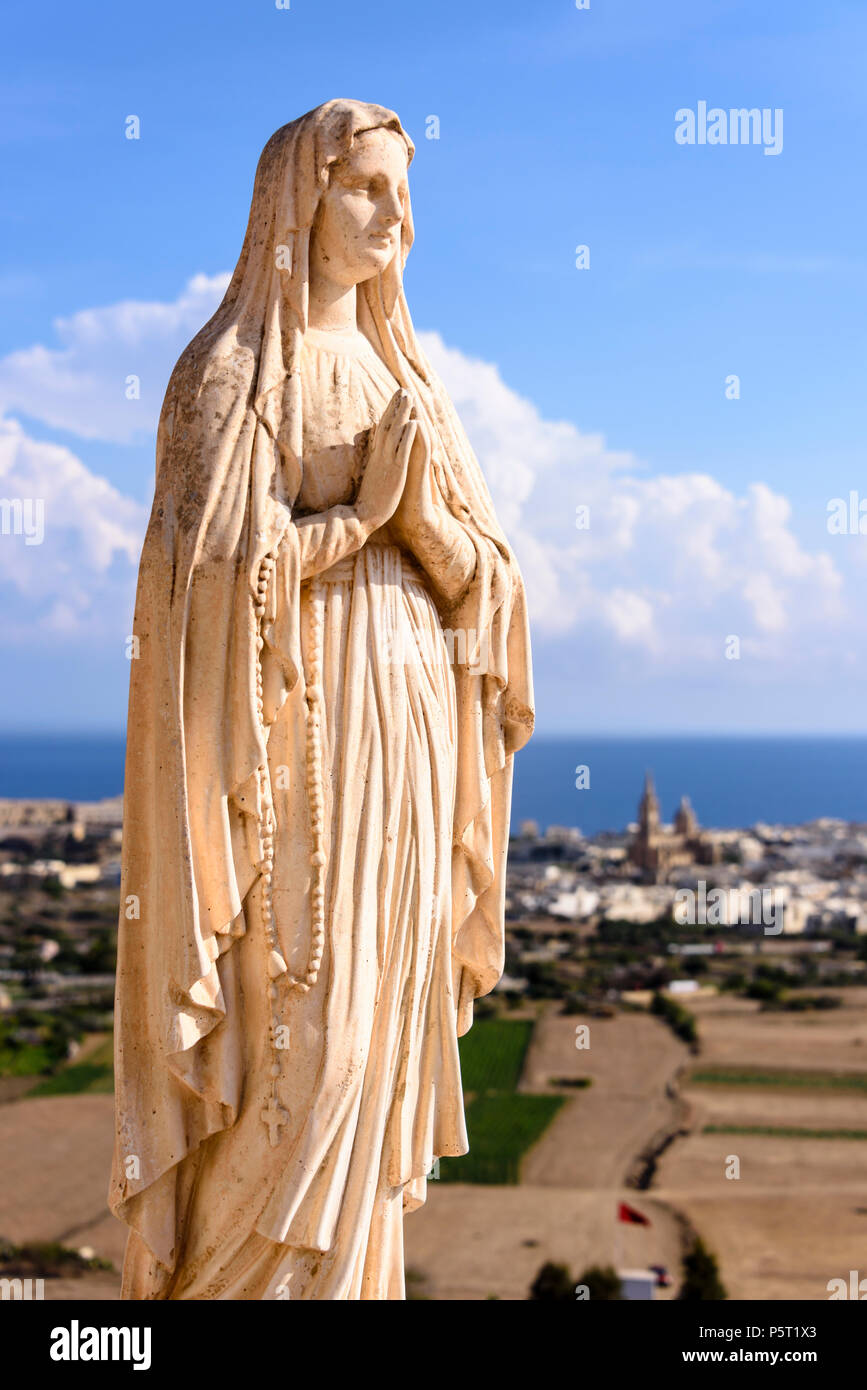 A statue of the Virgin Mary stands at the top of a hill in Gozo, Malta