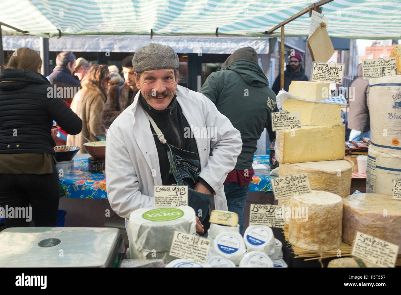 Charming Smiling Moustached Man Selling a Variety of Handmade Artisan Cheeses at Broadway Street Market in Hackney, London, England, UK, Europe. Stock Photo