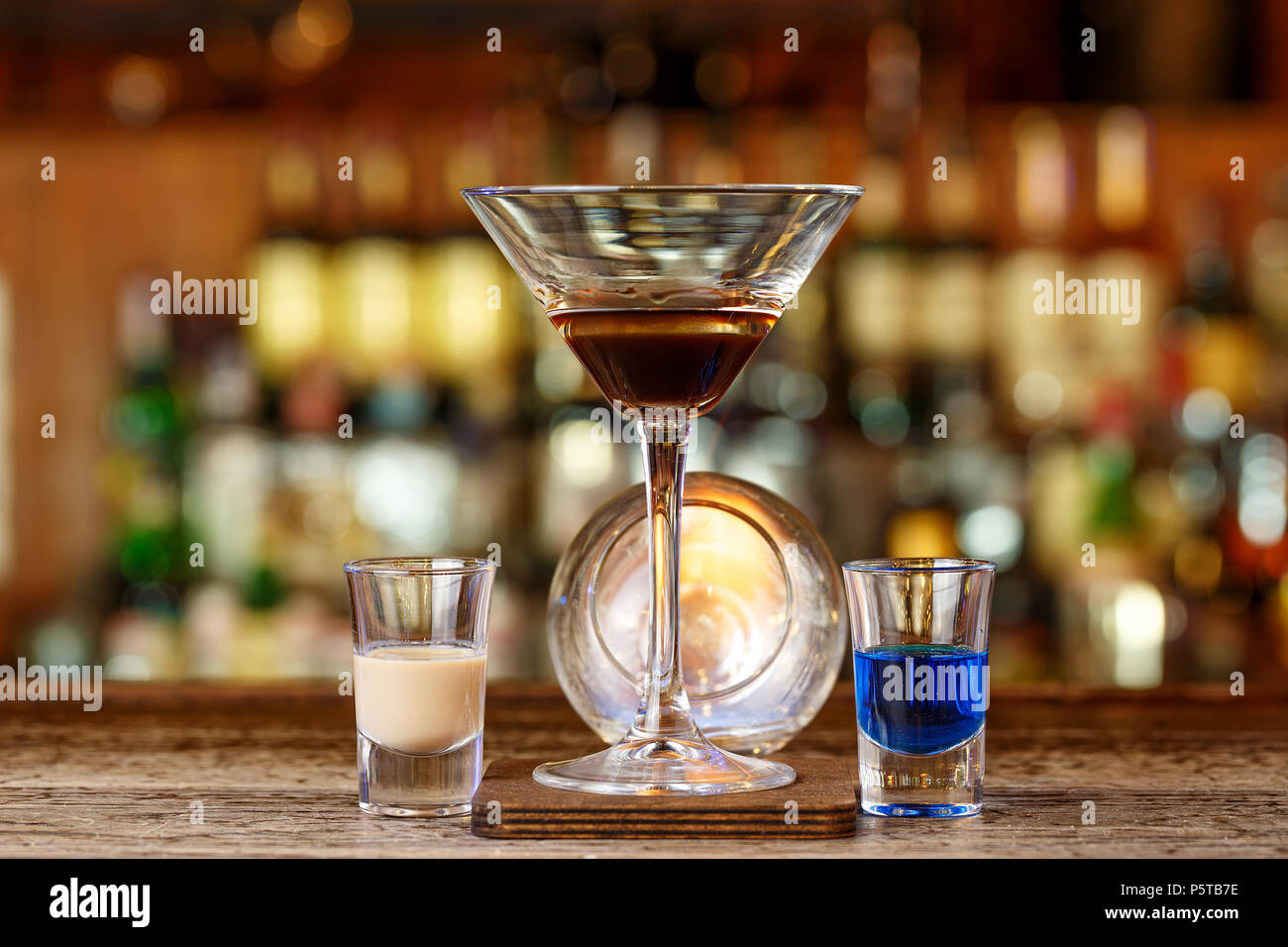 A cocktail based on sambuca and liqueurs stands on a wooden counter in