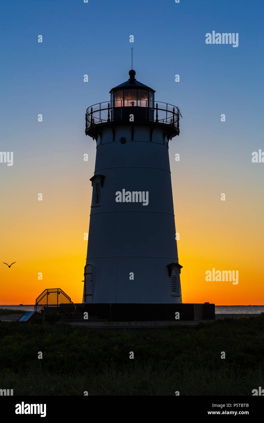 The rising sun adds color to the sky behind Edgartown Harbor Light in
